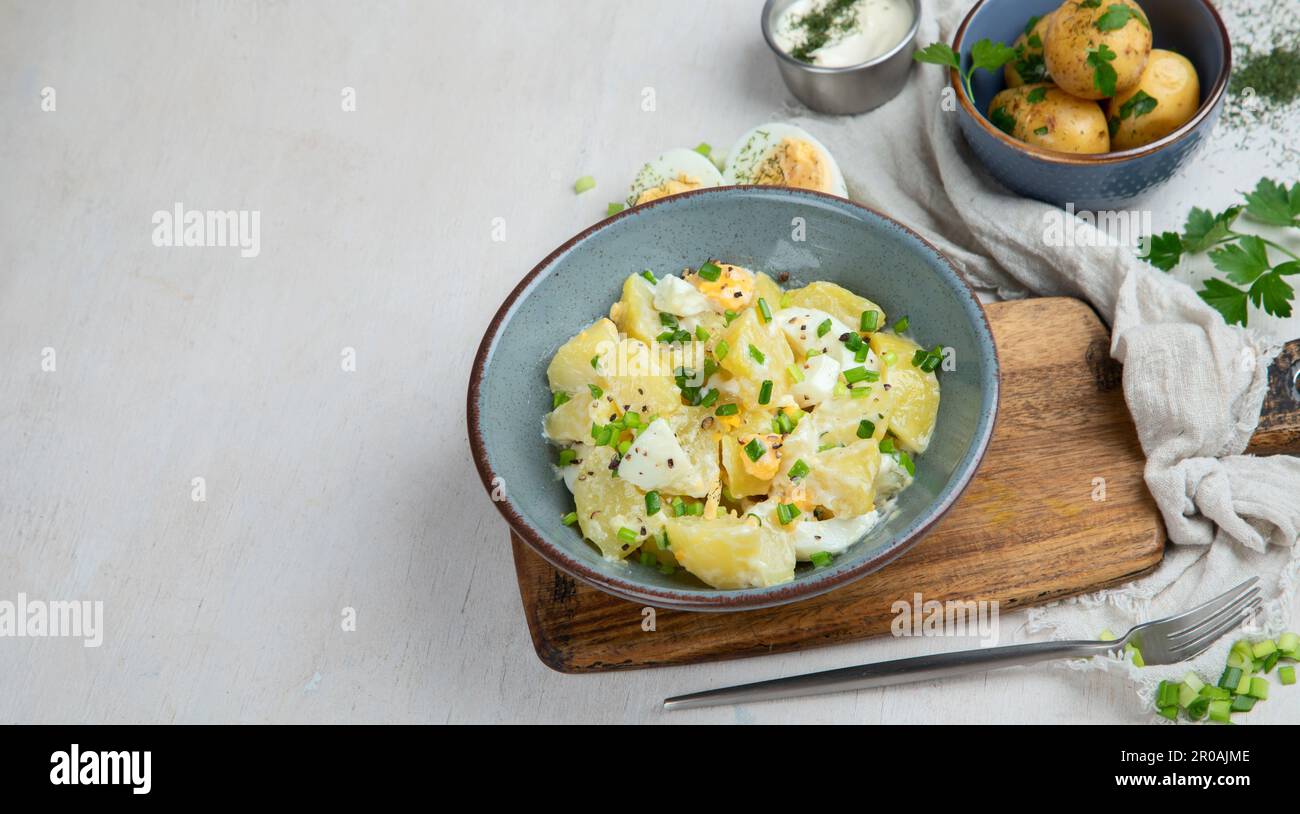 Salat aus Kartoffeln, Eiern, grünen Zwiebeln und Mayonnaise auf einem Teller auf weißem Hintergrund, Draufsicht. Panorama mit Kopierbereich. Stockfoto
