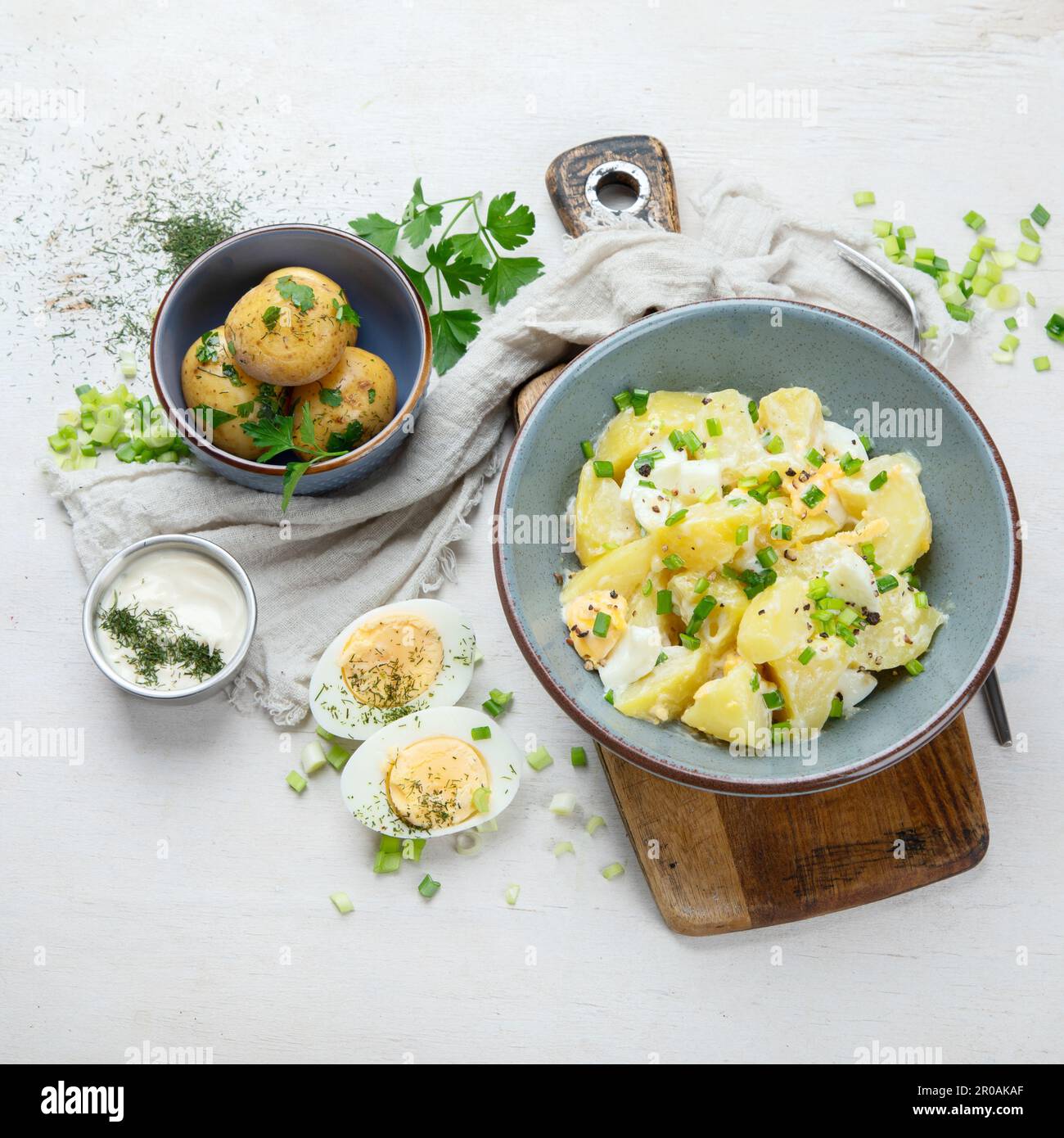 Salat aus Kartoffeln, Eiern, grünen Zwiebeln und Mayonnaise auf einem Teller auf weißem Hintergrund, Draufsicht. Stockfoto