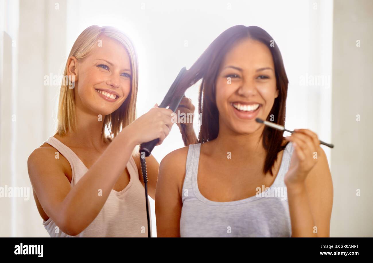 Der beste Freund, den eine Frau haben kann. Eine junge Frau, die sich schminkt, während ihr Freund ihr Haar glättet. Stockfoto