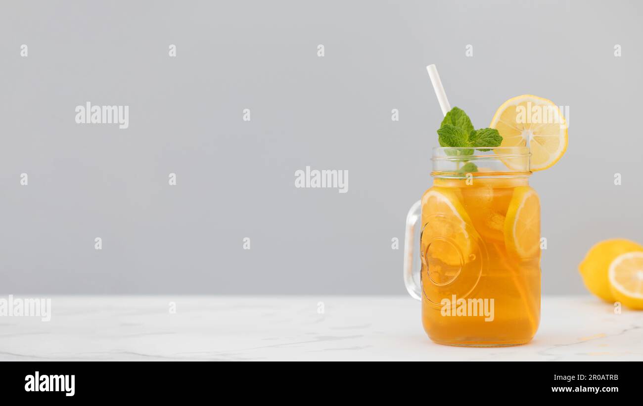 Ein Glas kalten Tee, Eiswürfel, Zitronenscheiben und einen Pfefferminzzweig. Kühle Sommergetränke. Stockfoto