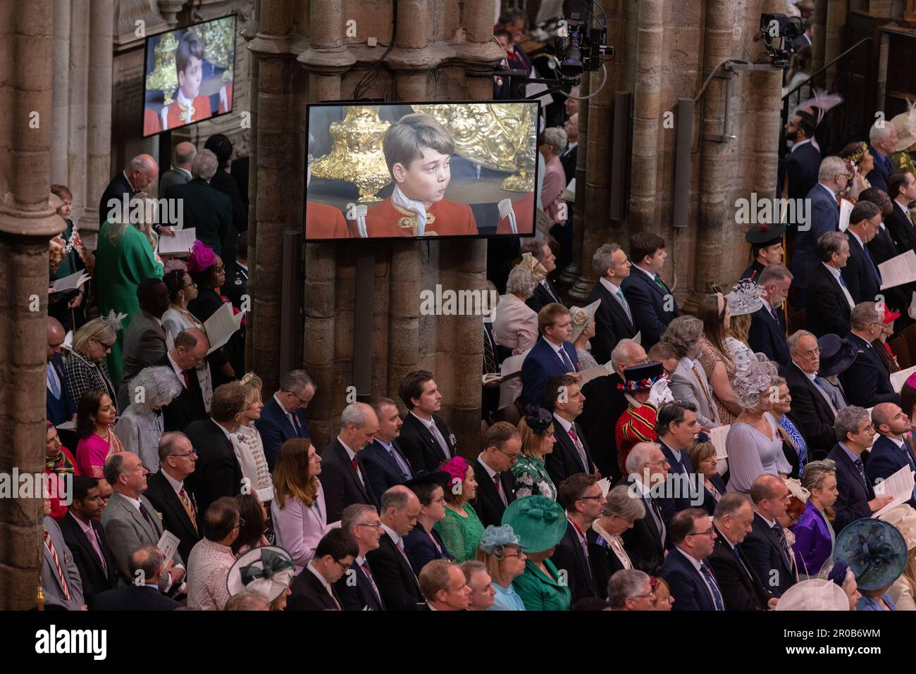 Gäste und Mitglieder der Gemeinde sehen die Krönungsrituale auf Leinwänden in der Westminster Abbey von König Karl III. Und Königsgemahnung. Stockfoto