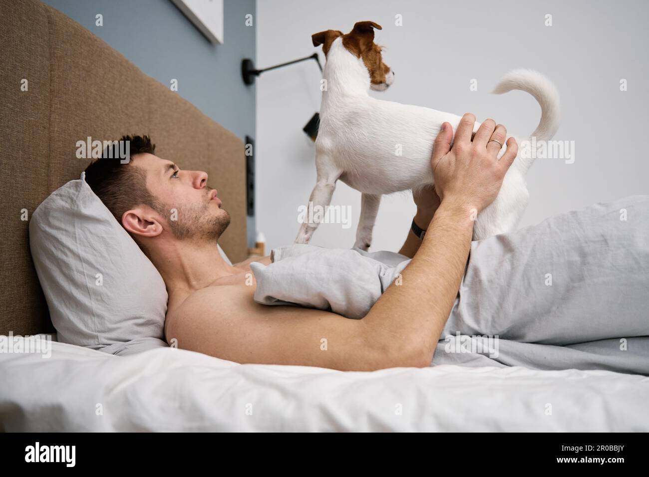 Mann mit Hund schläft auf dem Bett. Liebeskummer. Fauler Morgen mit Haustier Stockfoto