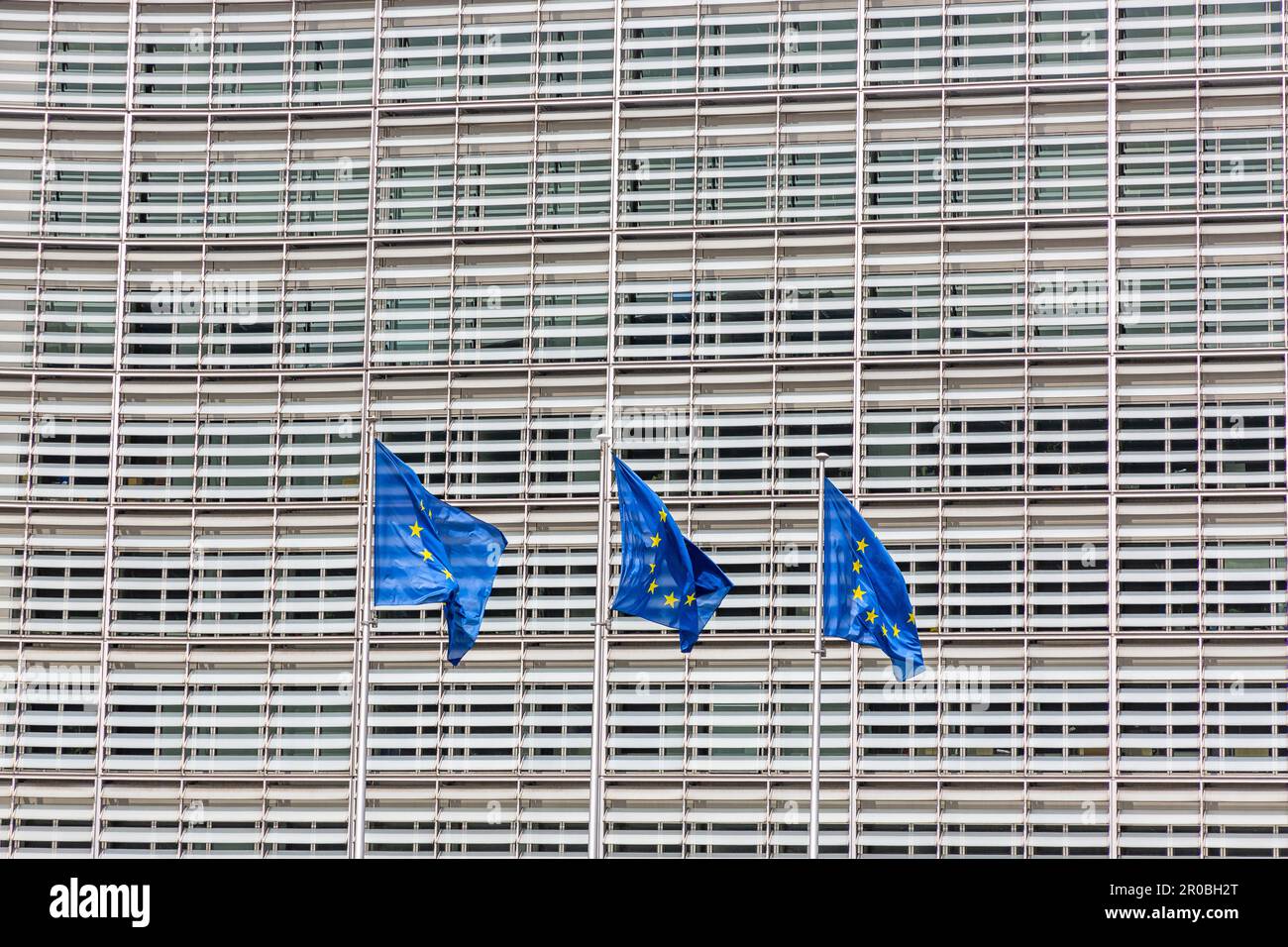 Drei Flaggen der Europäischen Union, die vor der Fassade des Berlaymont, dem Sitz der Europäischen Kommission in Brüssel, wackeln. Stockfoto