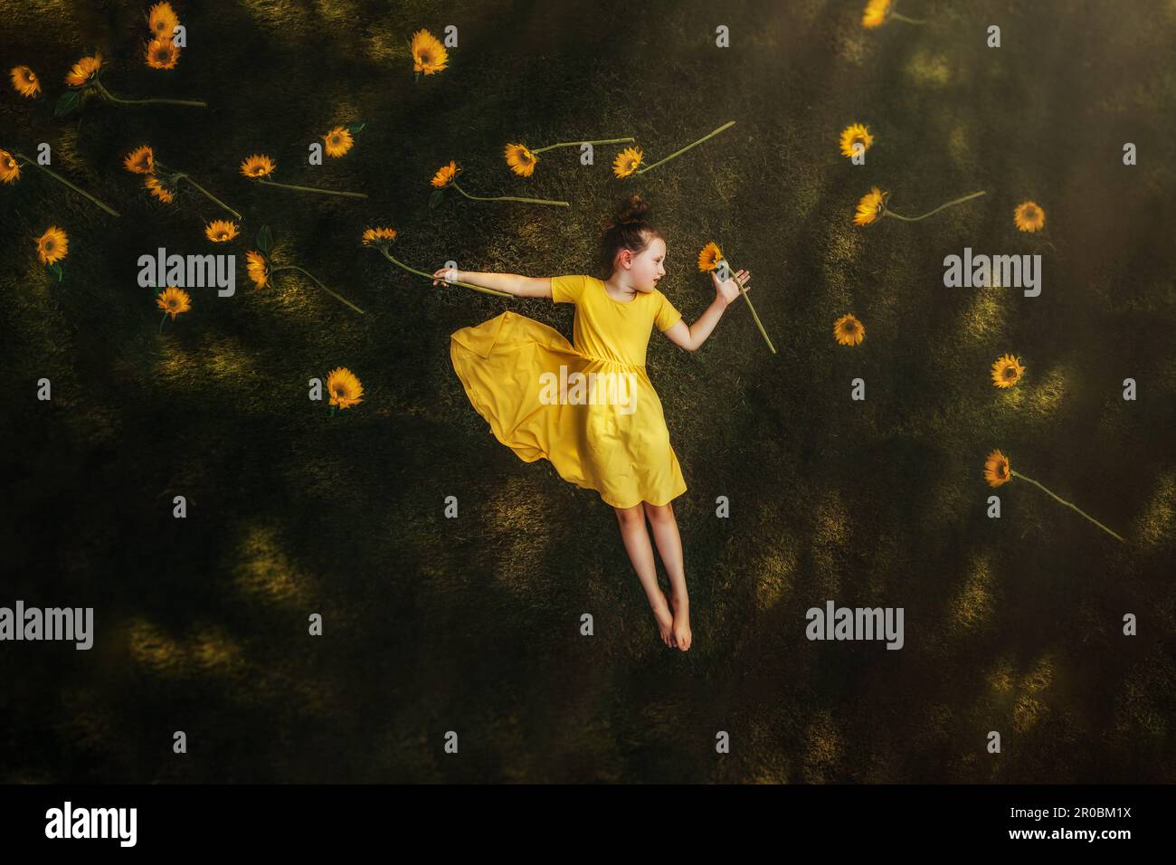 Ein Mädchen lag im Gras, umgeben von Sonnenblumen Stockfoto