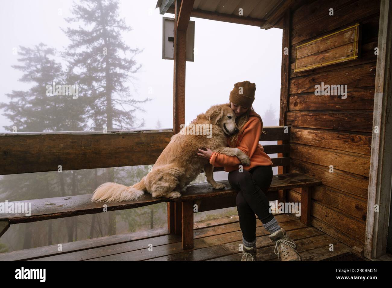 Süße flauschige Hunde- und Mädchenumarmung auf der Veranda der Hütte Stockfoto