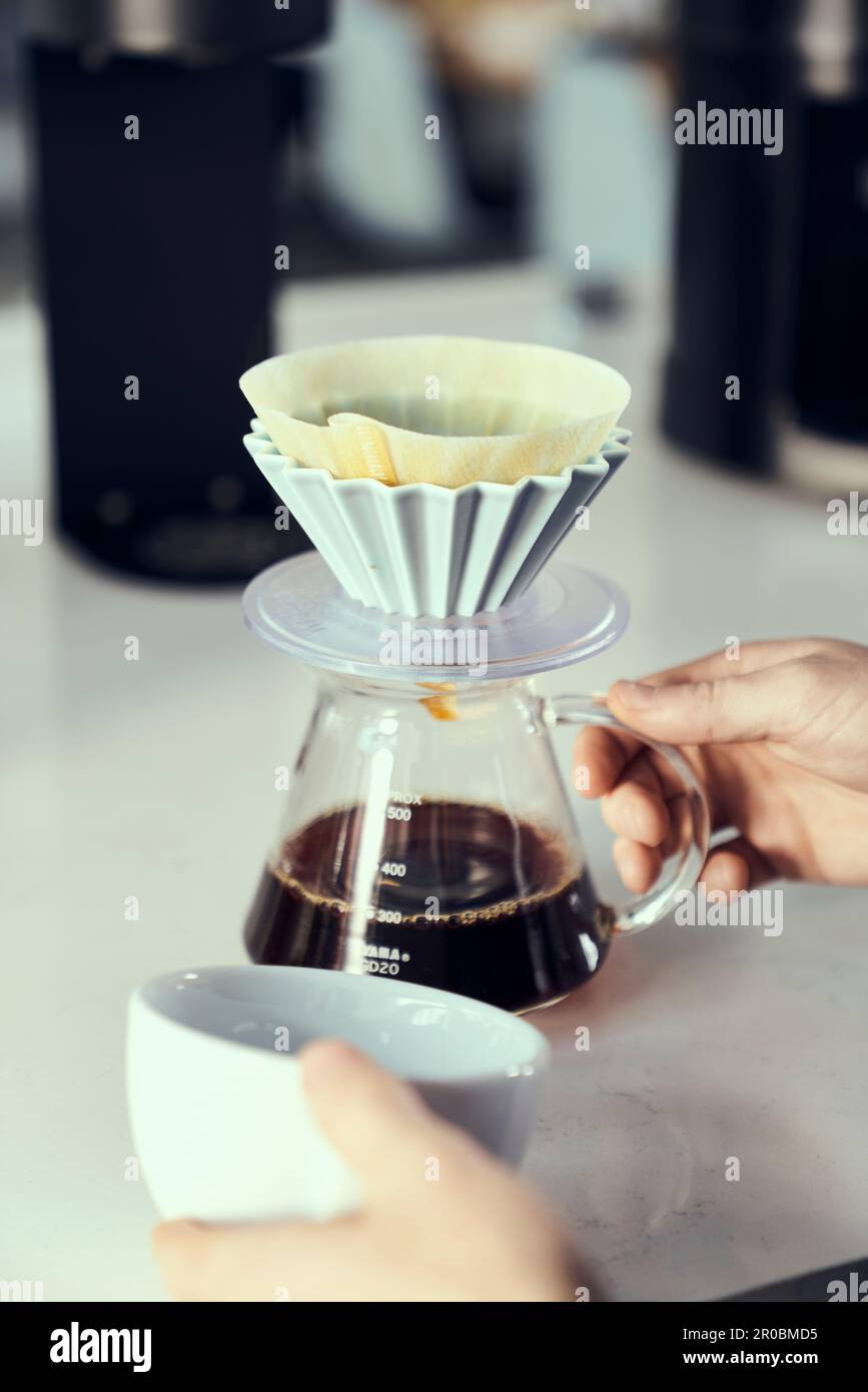 Ein Kaffeeüberlauf wird gleich in eine Tasse gegossen. Stockfoto
