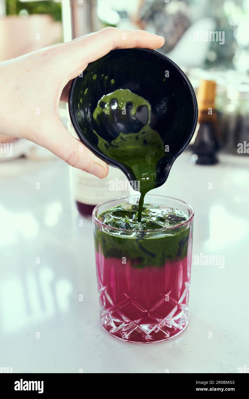 Eine Hand gießt grünen Matcha-Tee in stachelige Birnen-Limonade. Stockfoto