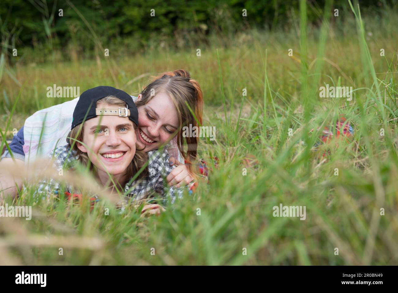Porträt eines jungen Paares, das auf der Wiese liegt und lächelt, Bayern, Deutschland Stockfoto