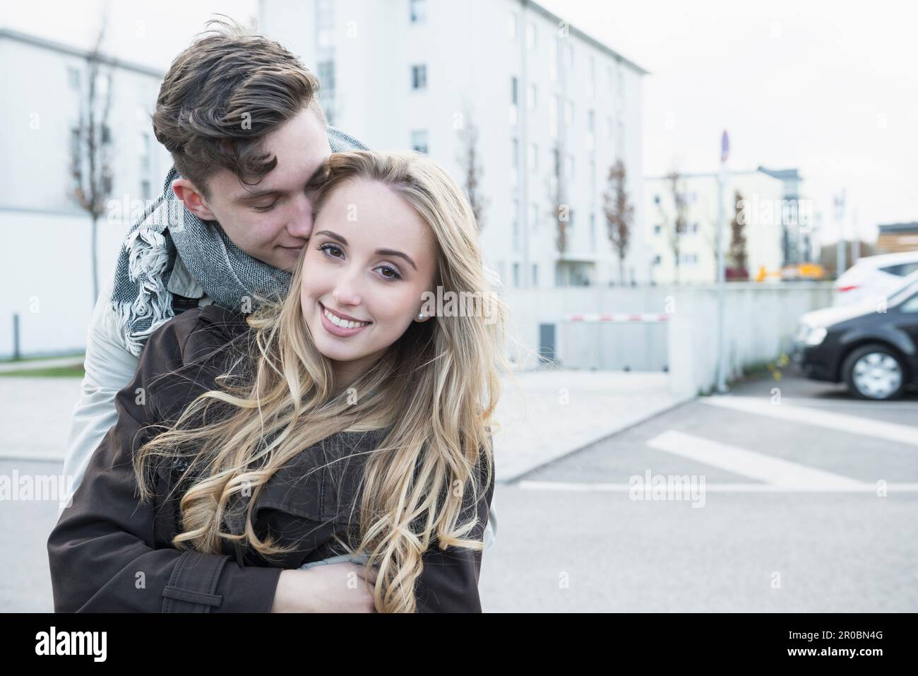 Ein junges Paar umarmt sich und lächelt in der Stadt München, Bayern, Deutschland Stockfoto