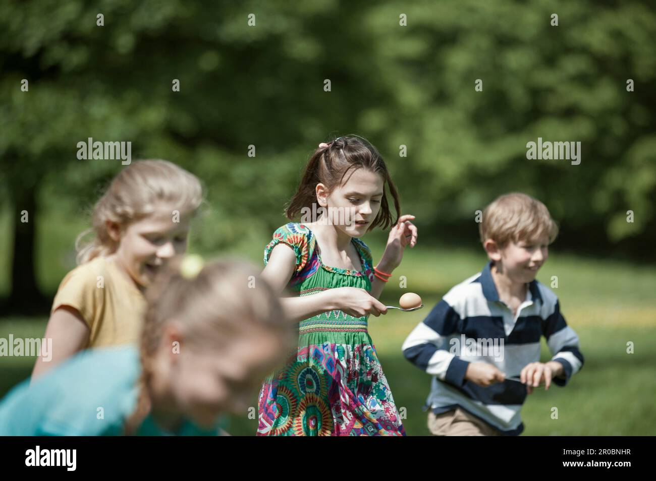 Gruppe von Kindern, die an einem Ei-Löffel-Rennen in einem Park in München, Bayern teilnehmen Stockfoto