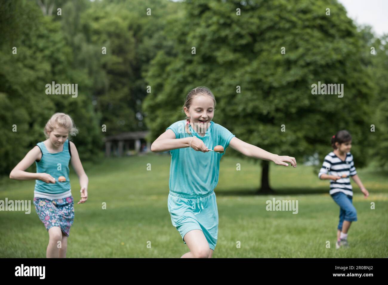 Eine Gruppe von Mädchen, die in einem Ei-Löffel-Rennen in einem Park in München, Bayern, Deutschland, gegeneinander antreten Stockfoto