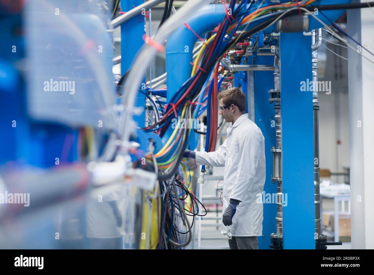 Junger männlicher Ingenieur, der eine Maschine in einem Industriebetrieb in Freiburg im Breisgau, Baden-WÃ¼rttemberg, Deutschland, untersucht Stockfoto