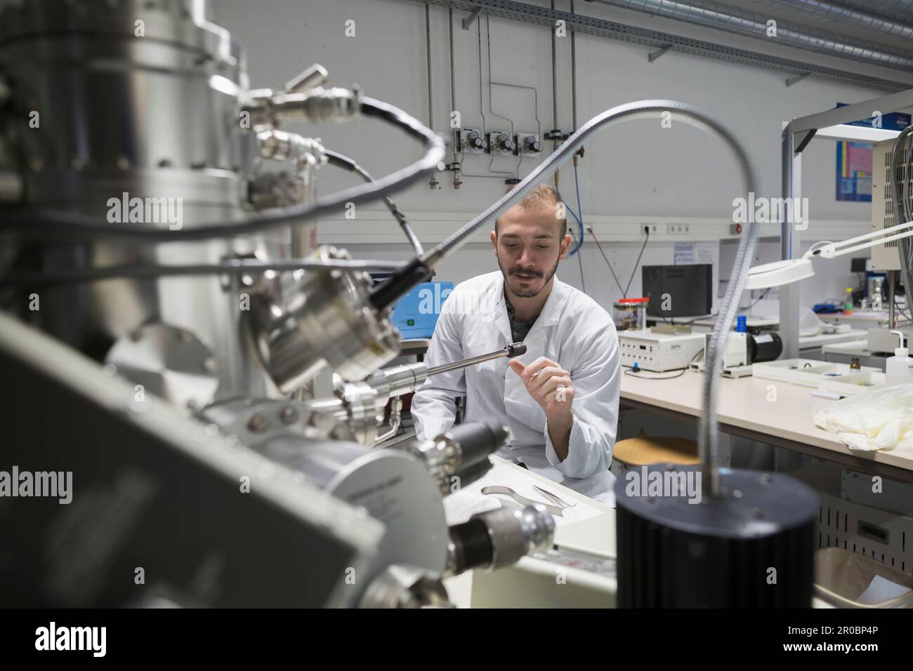 Junger männlicher Ingenieur, der eine Maschine in einem Industriebetrieb in Freiburg im Breisgau, Baden-WÃ¼rttemberg, Deutschland, untersucht Stockfoto