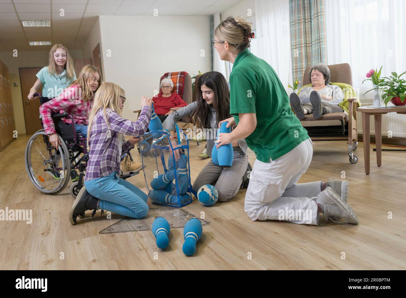 Mädchen, die mit Krankenschwestern und Seniorinnen im Altersheim Bowling spielen Stockfoto