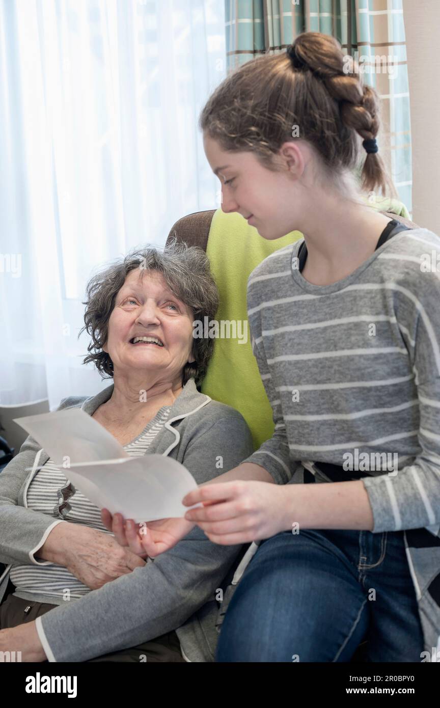 Enkelin zeigt Großmutter im Altersheim alte Fotos Stockfoto
