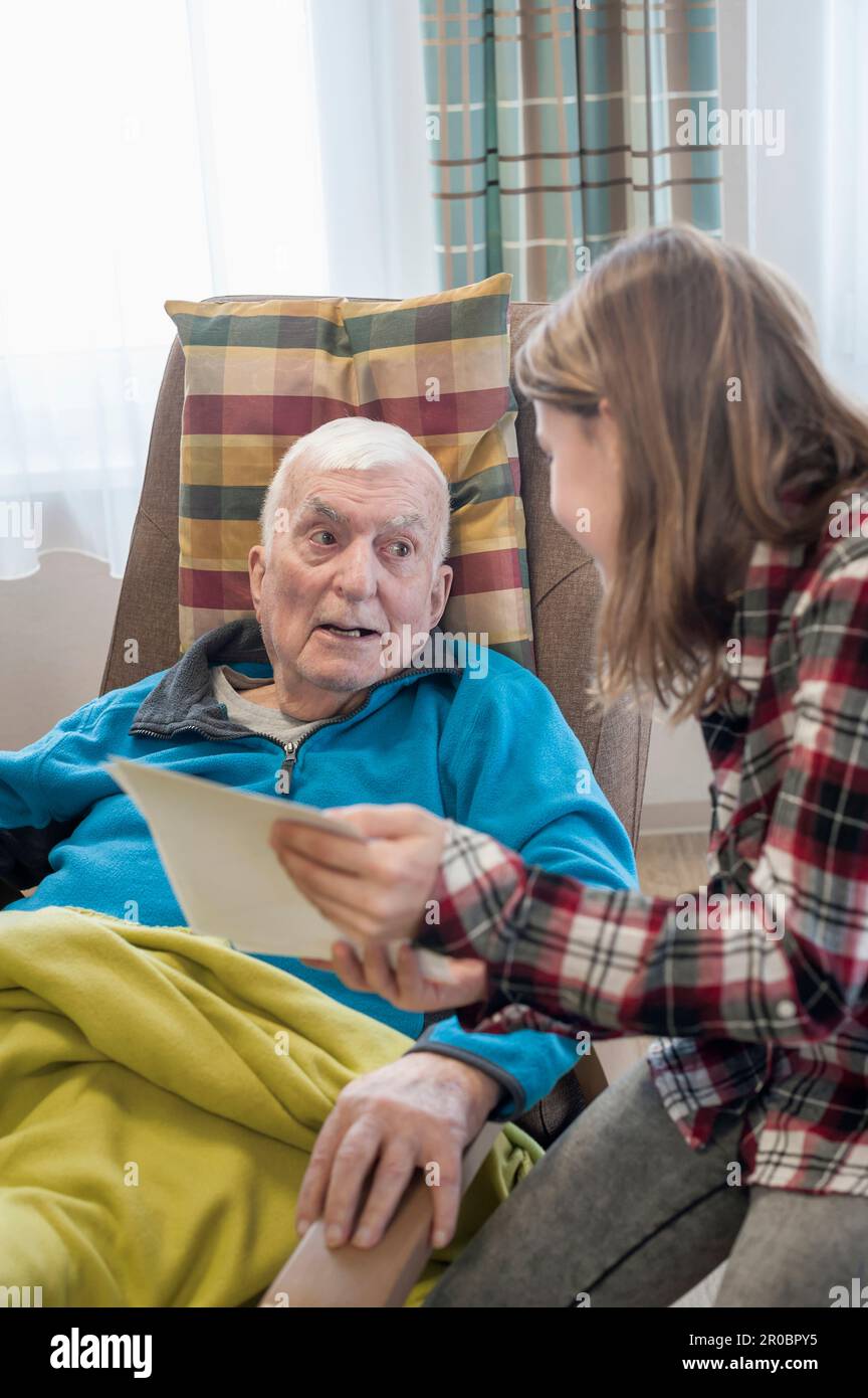 Enkelin zeigt Großvater im Altersheim alte Fotos Stockfoto