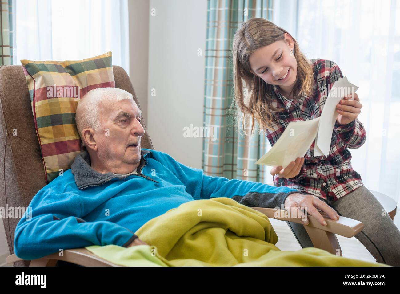 Enkelin zeigt Großvater im Altersheim alte Fotos Stockfoto