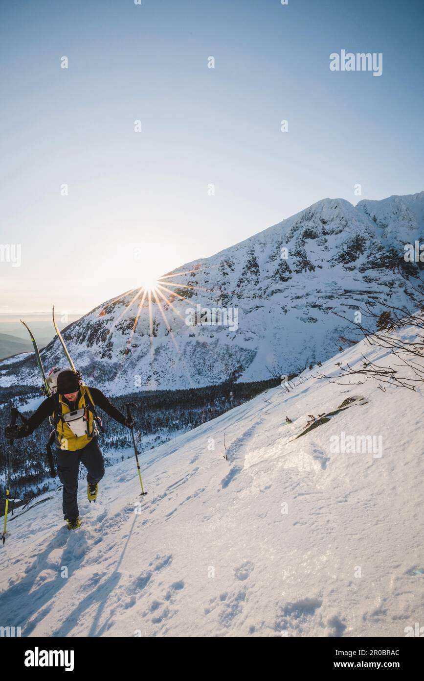 Männlicher Wanderer steigt bei Sonnenaufgang in Richtung des verschneiten Gipfels von Katahdin Stockfoto