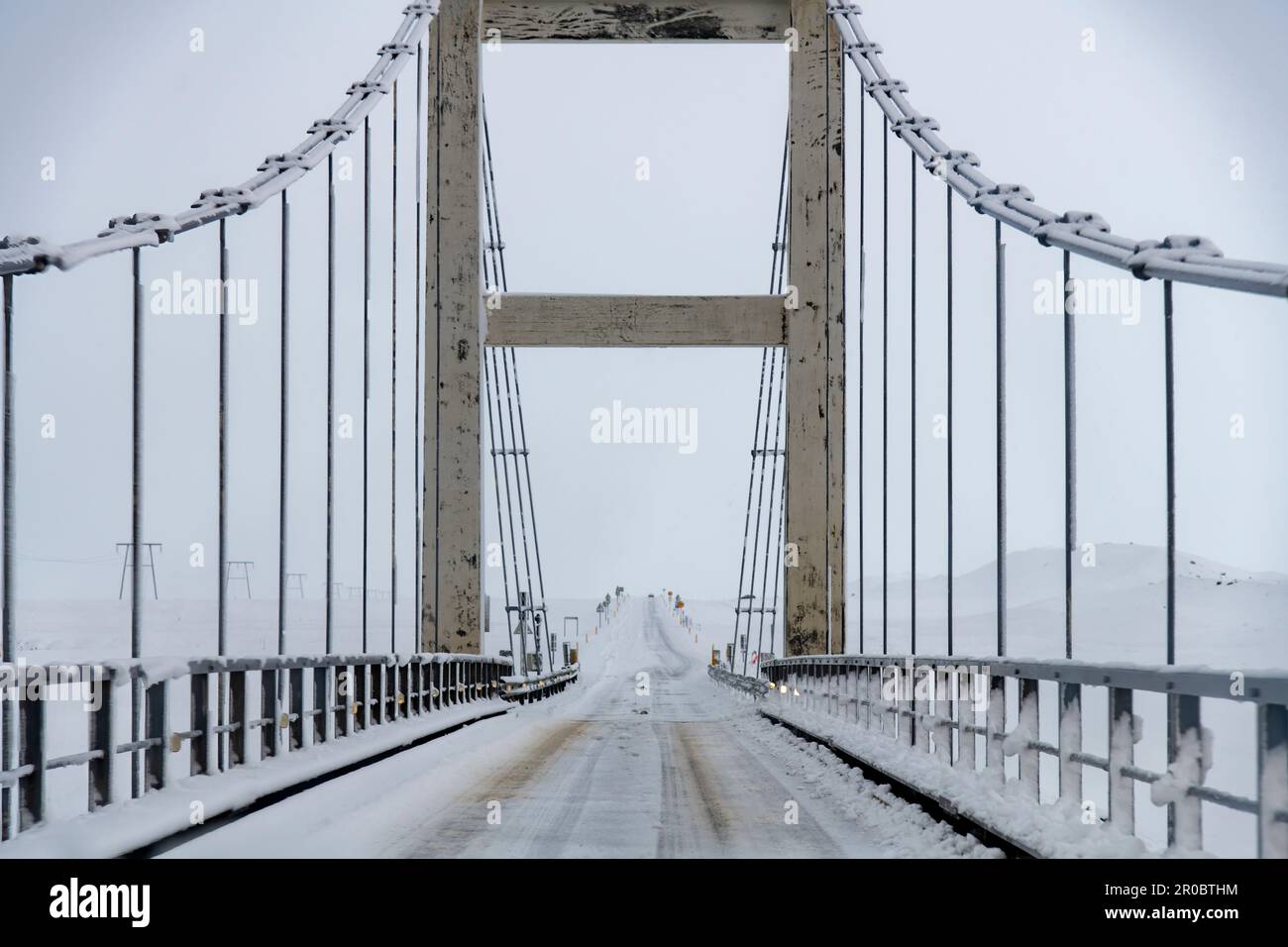 Aus der Perspektive des Fahrers auf der Hängebrücke über den Fluss Jökulsá, der die Gletscherlagune Jokulsarlon bei starkem Schneesturm mit dem Meer verbindet Stockfoto