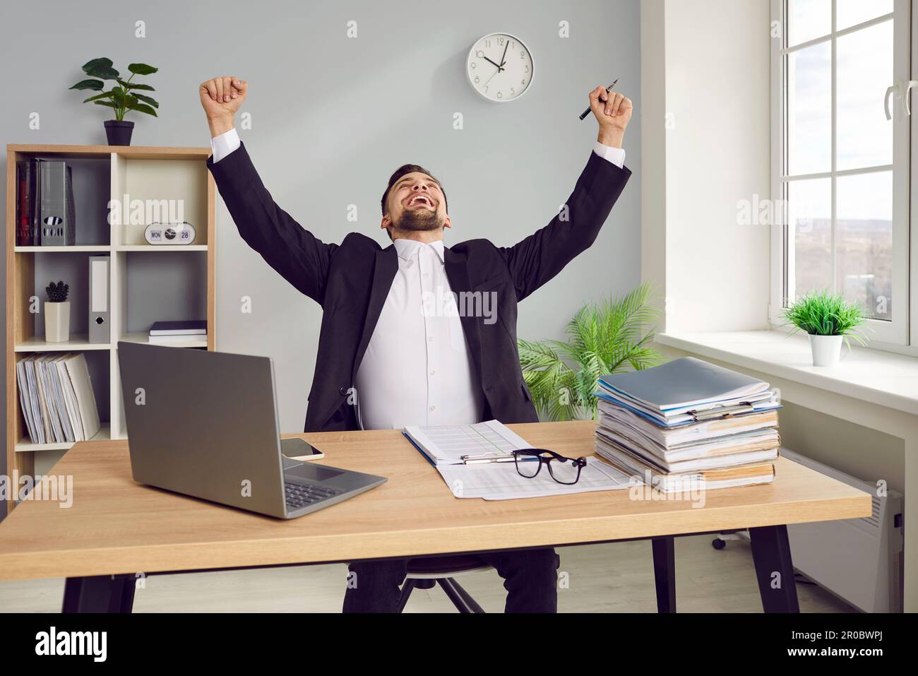 Ein junger männlicher Mitarbeiter freut sich, seine Arbeit zu beenden und frei vom Büro zu sein Stockfoto