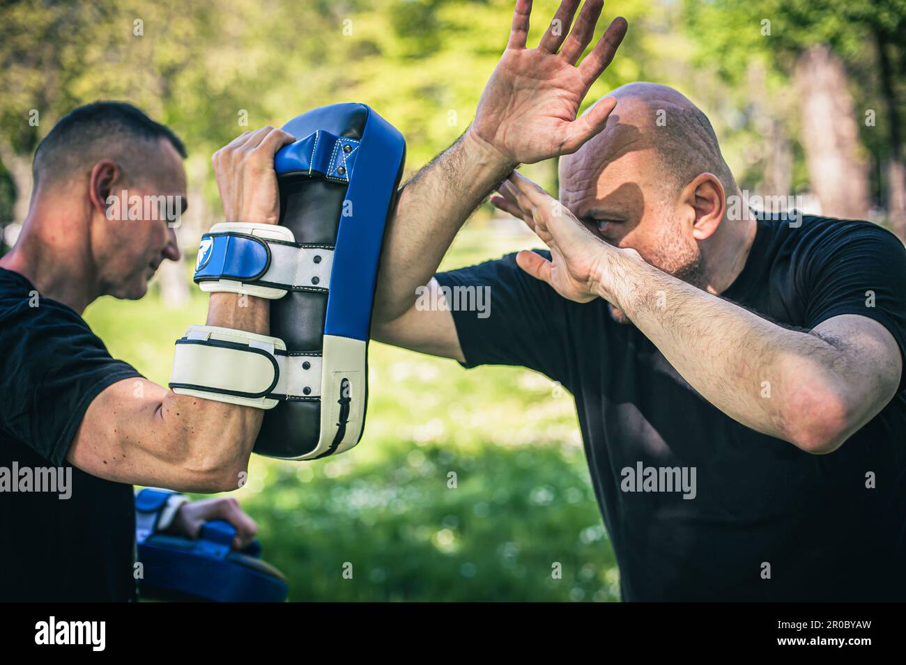 Muay thai-Trainer hält fokussierte Handschuhe. Ellenbogen-Kick-Technik-Training und Demonstration mit Pads. Kampfsportübungen Stockfoto