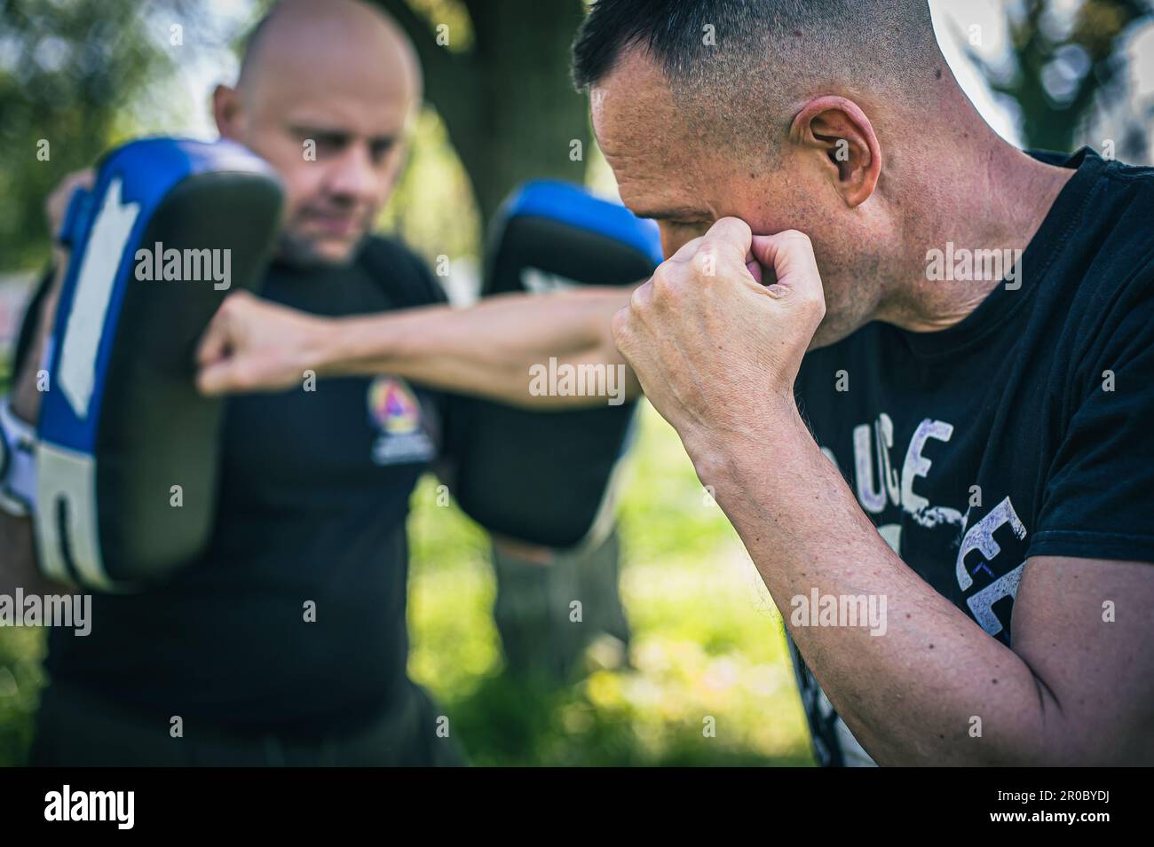 Muay thai-Trainer hält fokussierte Handschuhe. Kickboxtraining und Vorführung mit Pads. Kampfsportübungen Stockfoto