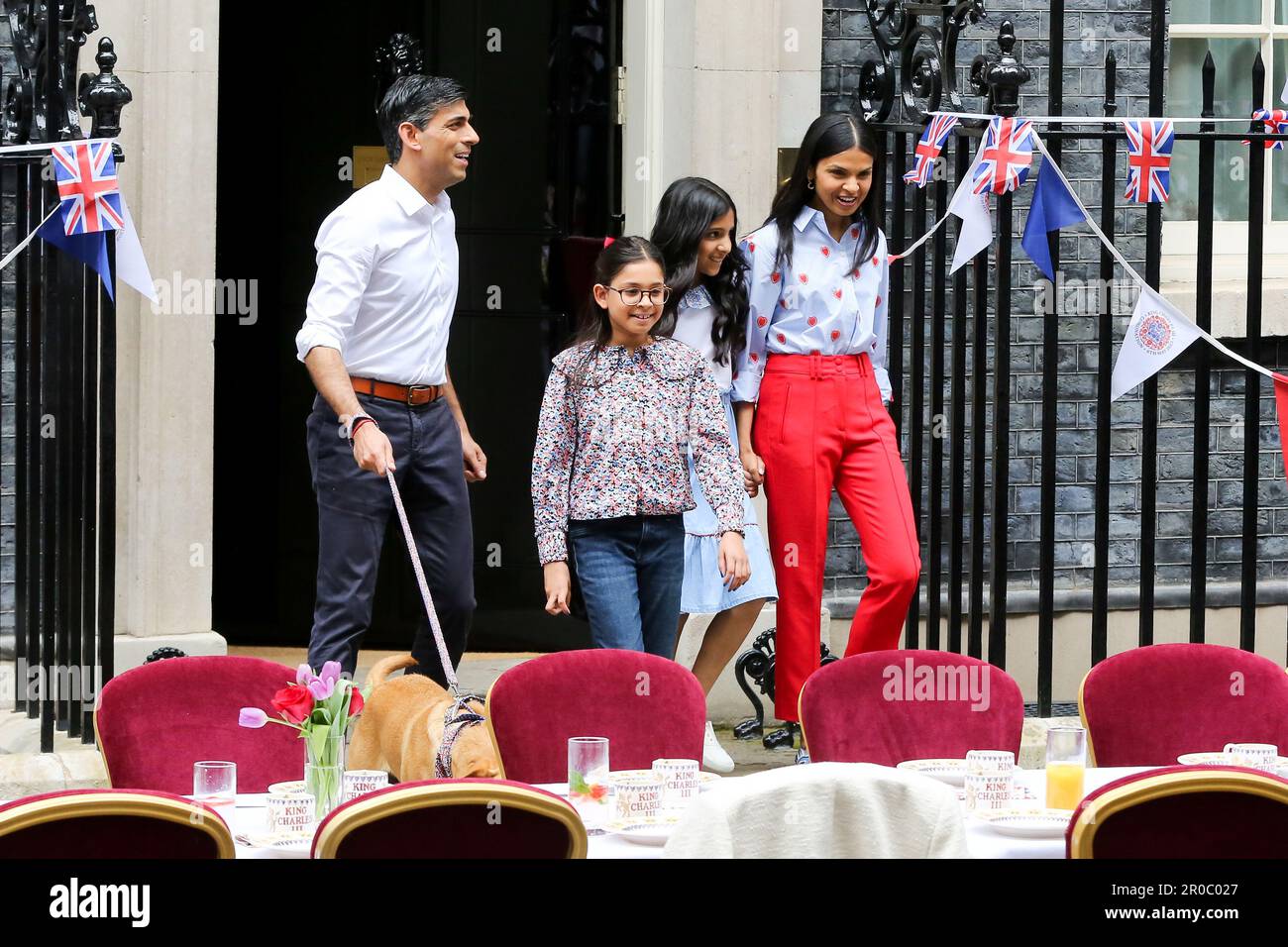 London, UK, 7. Mai 2023. Premierminister Rishi Sunak (L) und seine Frau Akshata Murty (R) und die Töchter Krishna Sunak (2. von L), Anoushka Sunak (2. von R) und der Familienhund Nova kommen aus nicht 10 heraus, um die Gäste zu begrüßen. Premierminister Rishi Sunak und seine Frau Akshata Murty veranstalten in der Downing Street, Westminster, ein großes Krönungsessen für Mitglieder der Gemeinde, Wohltätigkeitsorganisationen, Freiwillige und Menschen aus der Ukraine, die nach dem Ausbruch der russischen Invasion im Vereinigten Königreich leben. Die Nation feiert weiterhin die Krönung von König Karl III. Und Königin Camilla am 6. MJ 2023 als Big Cor Stockfoto