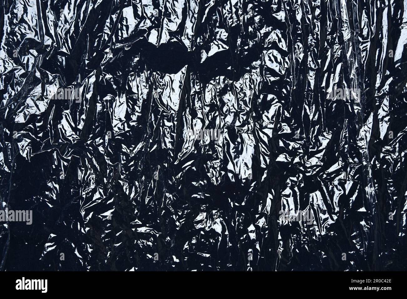 Plastikverpackung aus Polyethylen auf schwarzem Hintergrund abdecken. Transparente Stretchfolienstruktur aus Kunststoff. Transparente Kunststofffolie Stockfoto