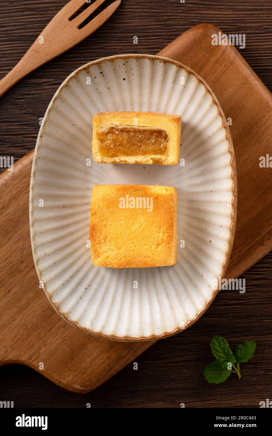 Köstliches taiwanesisches berühmtes Ananaskuchen Gebäck als Dessert auf einem Teller auf einem Holztisch mit heißem Tee. Stockfoto