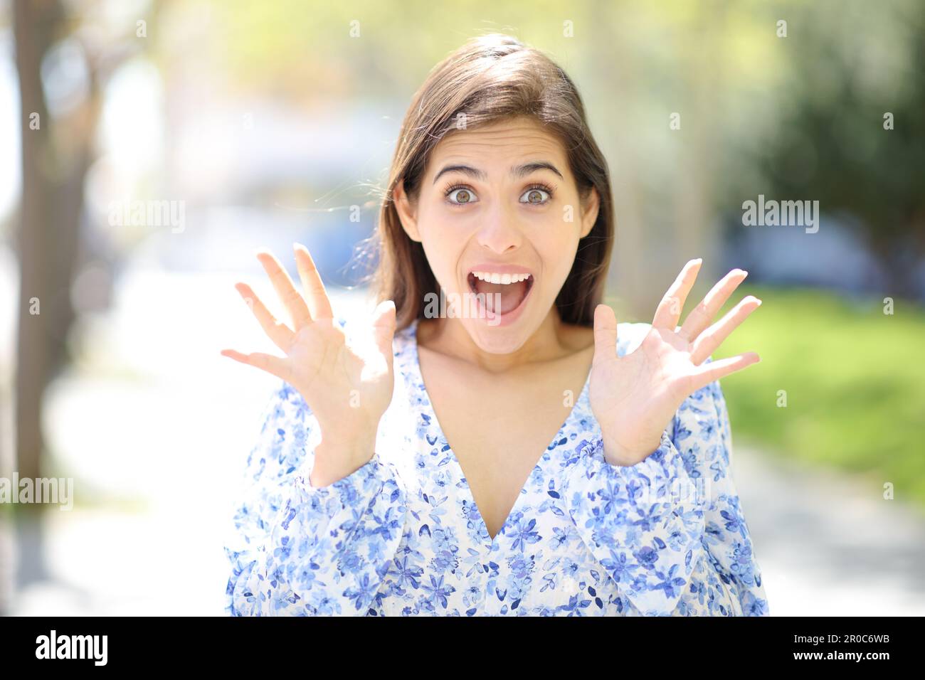 Vorderansicht einer erstaunten Frau, die auf der Straße in die Kamera schaut Stockfoto