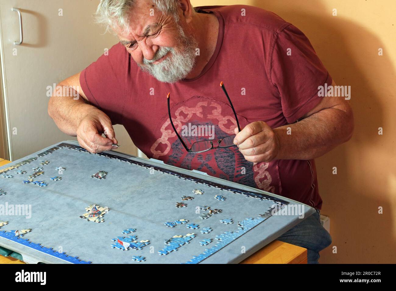 Älterer oder älterer Mann, der Probleme hat, ein Puzzle zu lösen. Stockfoto