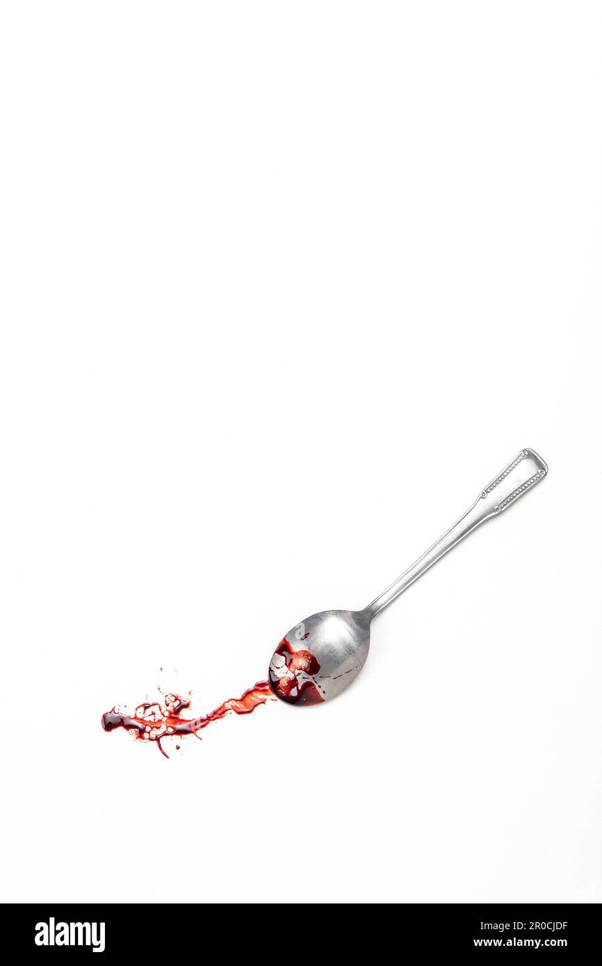 Weißer Hintergrund mit blutüberzogenem Teelöffel Stockfoto