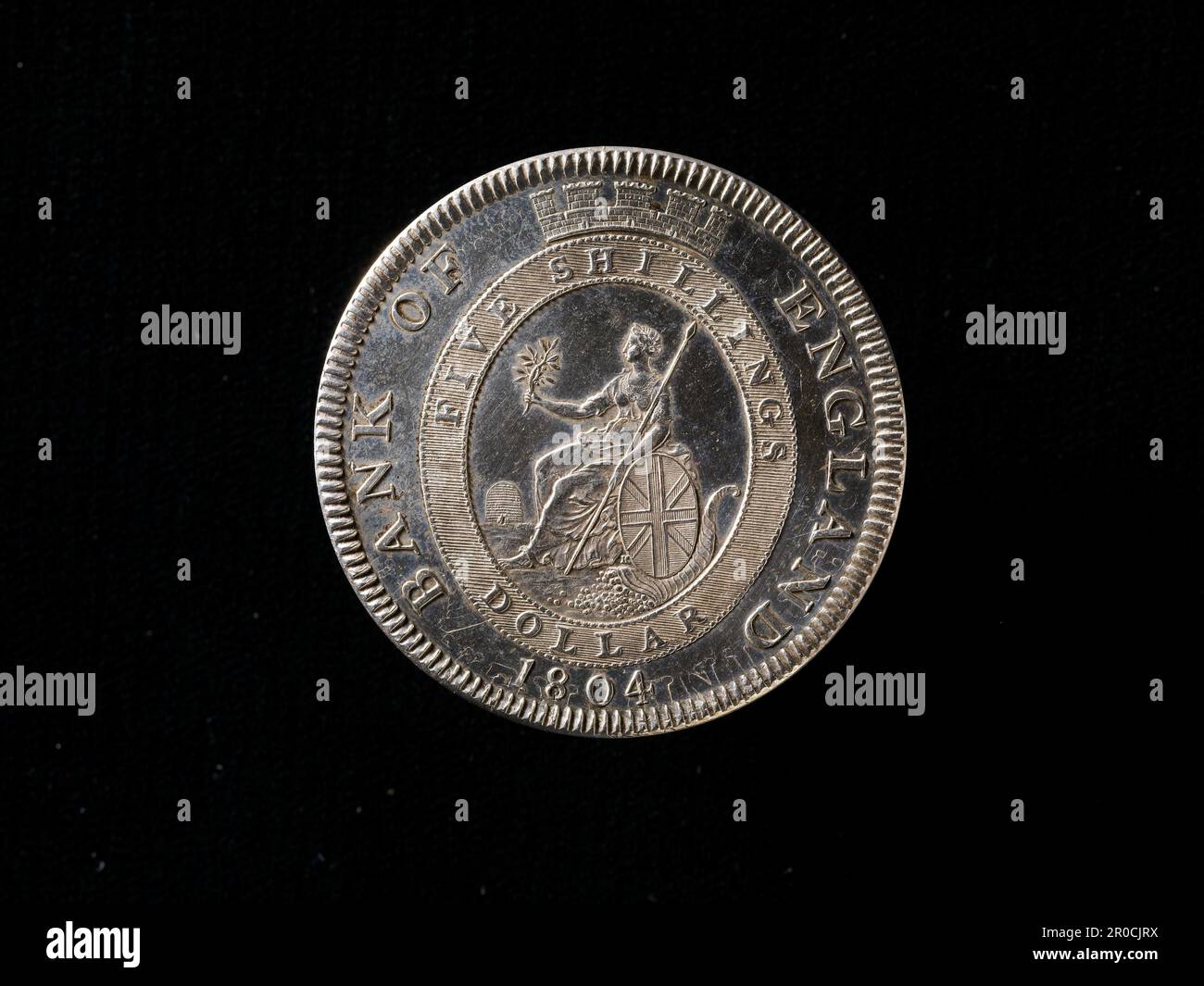 [Reverse] (Umkehren). Die Bank of England regenerierte Britannia Dollar fünf-Schilling-Token, 1804. Hersteller: Matthew Boulton, Münzanstalt Soho. Hersteller: Münzprägeanstalt Soho. Graviererin Conrad Heinrich Küchler. SCHRÄG: GEORGIUS III DEI GRATIA REX. Der Preisträger und die drapierte Büste von George III., die nach rechts zeigt, mit Locken über beiden Schultern... Rückwärts:. BANK OF ENGLAND 1804 Britannia sitzt links mit Speer in der linken Hand und Lorbeerspray in der rechten Hand; mit ovalem Schild, mit den Kreuzen von St. George, St. Patrick und St. Andrew, heraldisch gefärbt. Hornhaut unter Schild und Ofen im Hintergrund. Alle im oval-Verbot Stockfoto