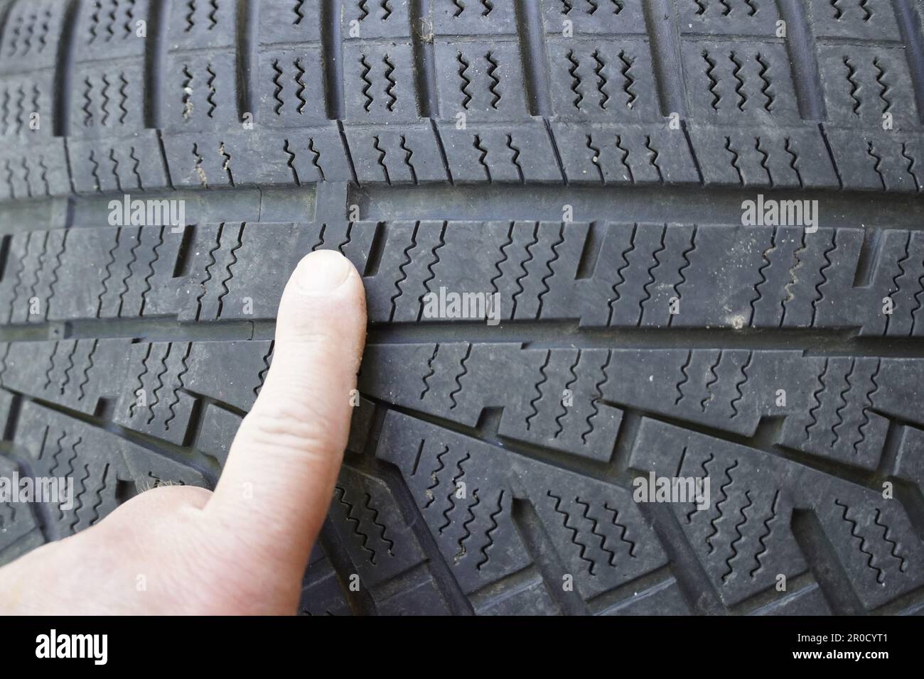 Prüfen der Reifenlauffläche mit Hilfe von Profilanzeigen in einer Nahaufnahme Stockfoto