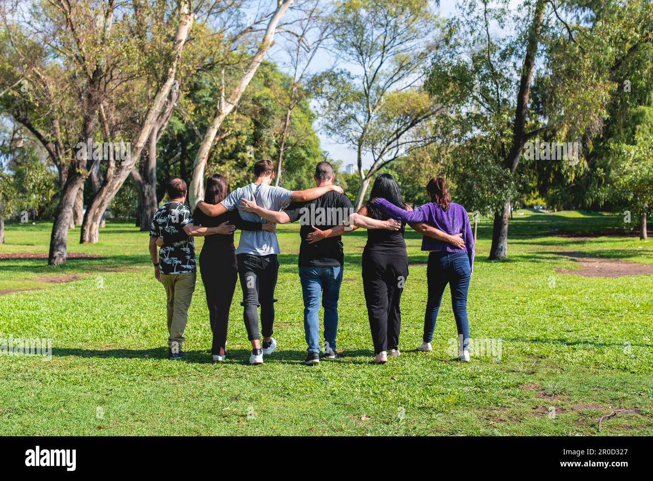 Rückansicht einer Gruppe von Freunden, die sich beim Gehen umarmen. Freundschafts- und Supportkonzept. Stockfoto