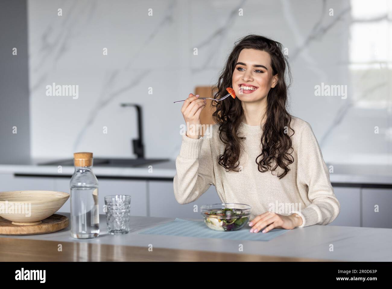 Junge Frau, die Salat isst und einen gemischten Salat hält. Stockfoto