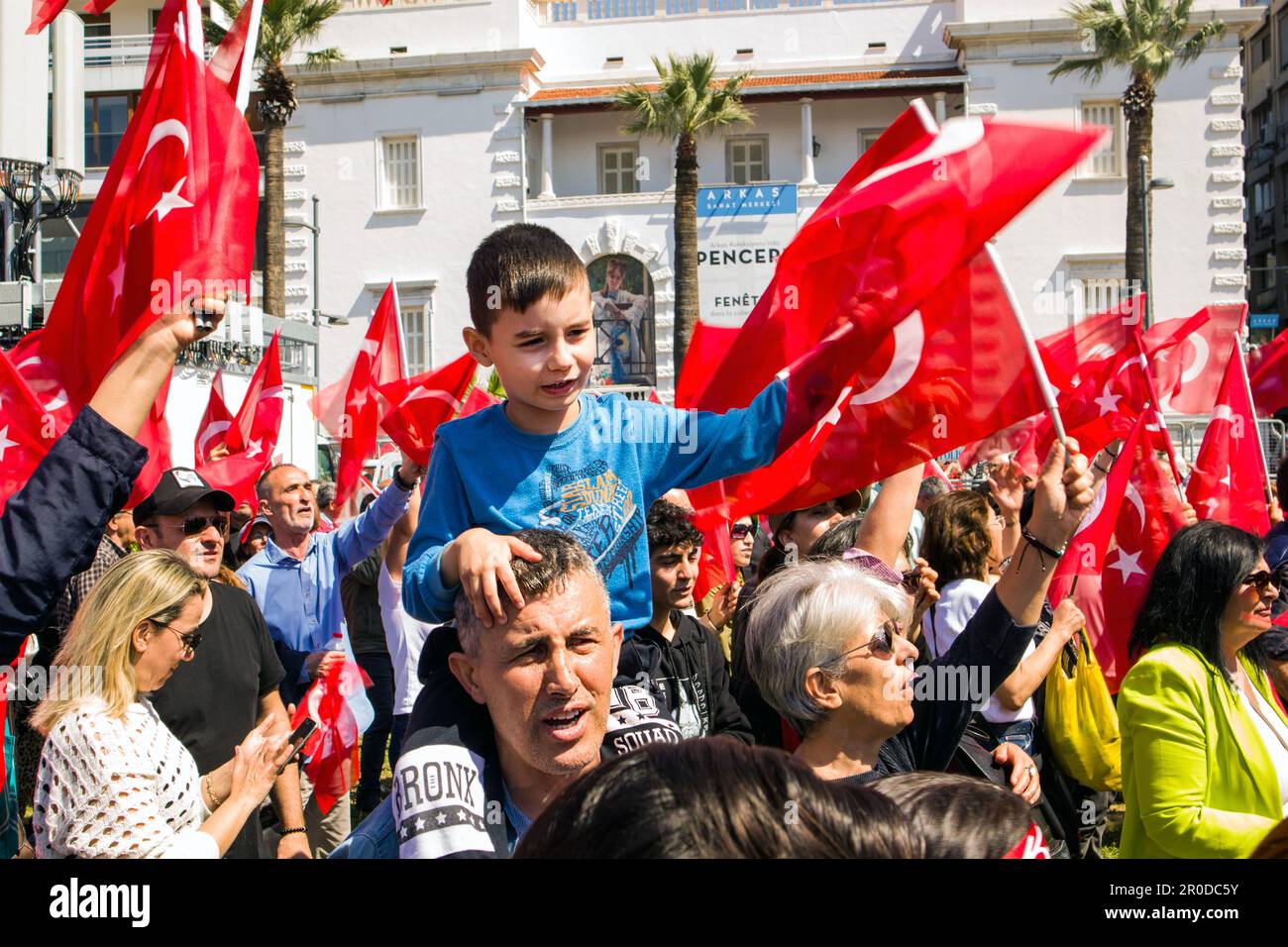 Izmir, Konak, Truthahn 04.30.2023 Ein schwarzhaariger türkischer Junge in einem blauen Hemd, sitzt auf der Schulter seines Vaters, winkt mit der türkischen Flagge, überfüllte Leute Stockfoto