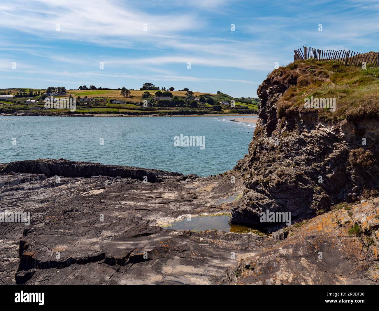 Eine Klippe am Ozean in Irland an einem sonnigen Sommertag. Irische Küstenlandschaft, klarer blauer Himmel, Felsformation in der Nähe des Wasserkörpers. Stockfoto