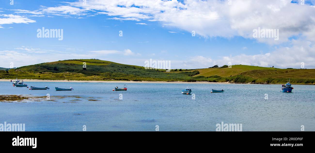 An einem sonnigen Sommertag liegen mehrere Boote in der Clonakilty Bay vor Anker. Blauer Himmel mit weißen Wolken über der wunderschönen irischen Küste. Boot auf dem Wasser Stockfoto