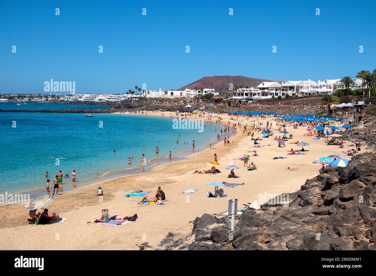 Blick auf Playa Dorada Beach, Playa Blanca, Lanzarote. Es ist ein warmer, sonniger Tag mit Urlaubern, die die Sonne an einem goldenen Strand genießen Stockfoto