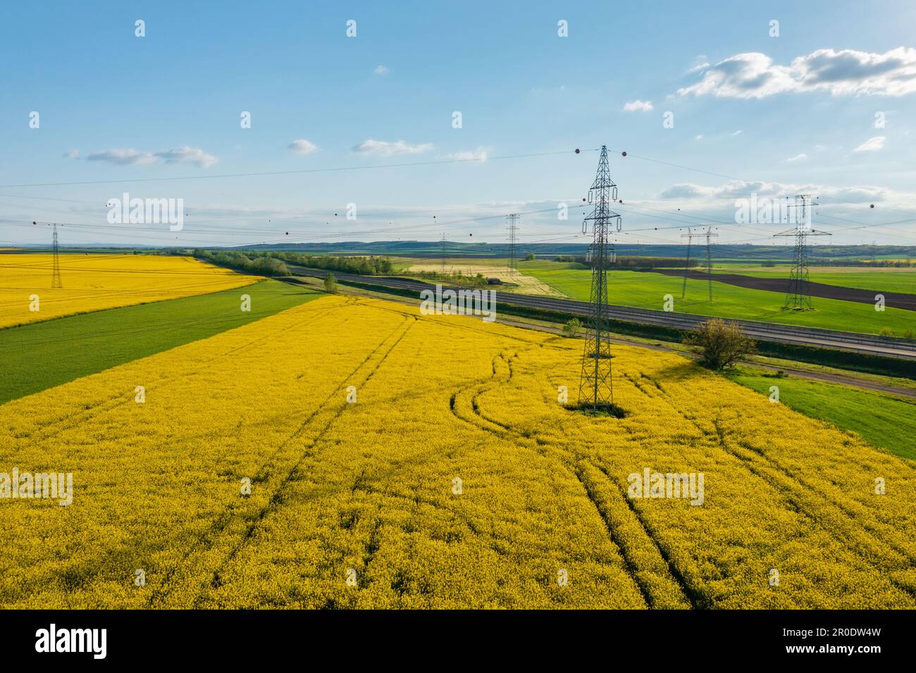 Luftaufnahme von Strommasten mit Stromleitungen über dem landwirtschaftlichen Feld. Stockfoto