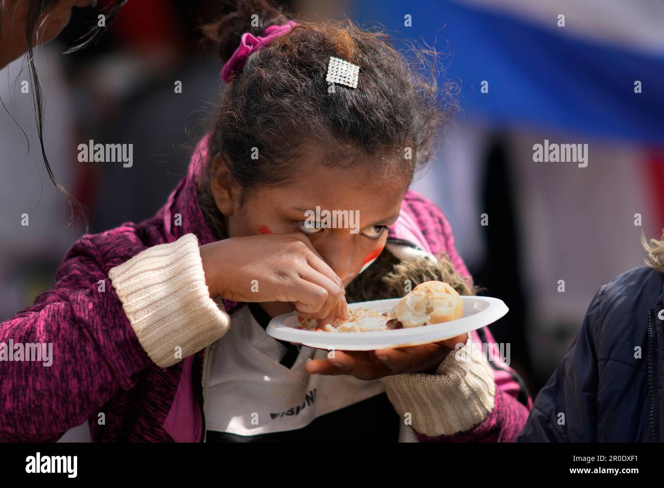 A woman eats complimentary food served at a protest against the detention of presidential candidate Parguayo Cubas and some of his supporters, as she eyes the police who stand guard nearby in Asuncion, Paraguay, Monday, Nov. 8, 2023. Police on Friday detained Cubas, a far-right populist who came in third in Sunday's presidential election and had alleged without evidence the vote was marred by fraud. (AP Photo/Jorge Saenz) Stockfoto