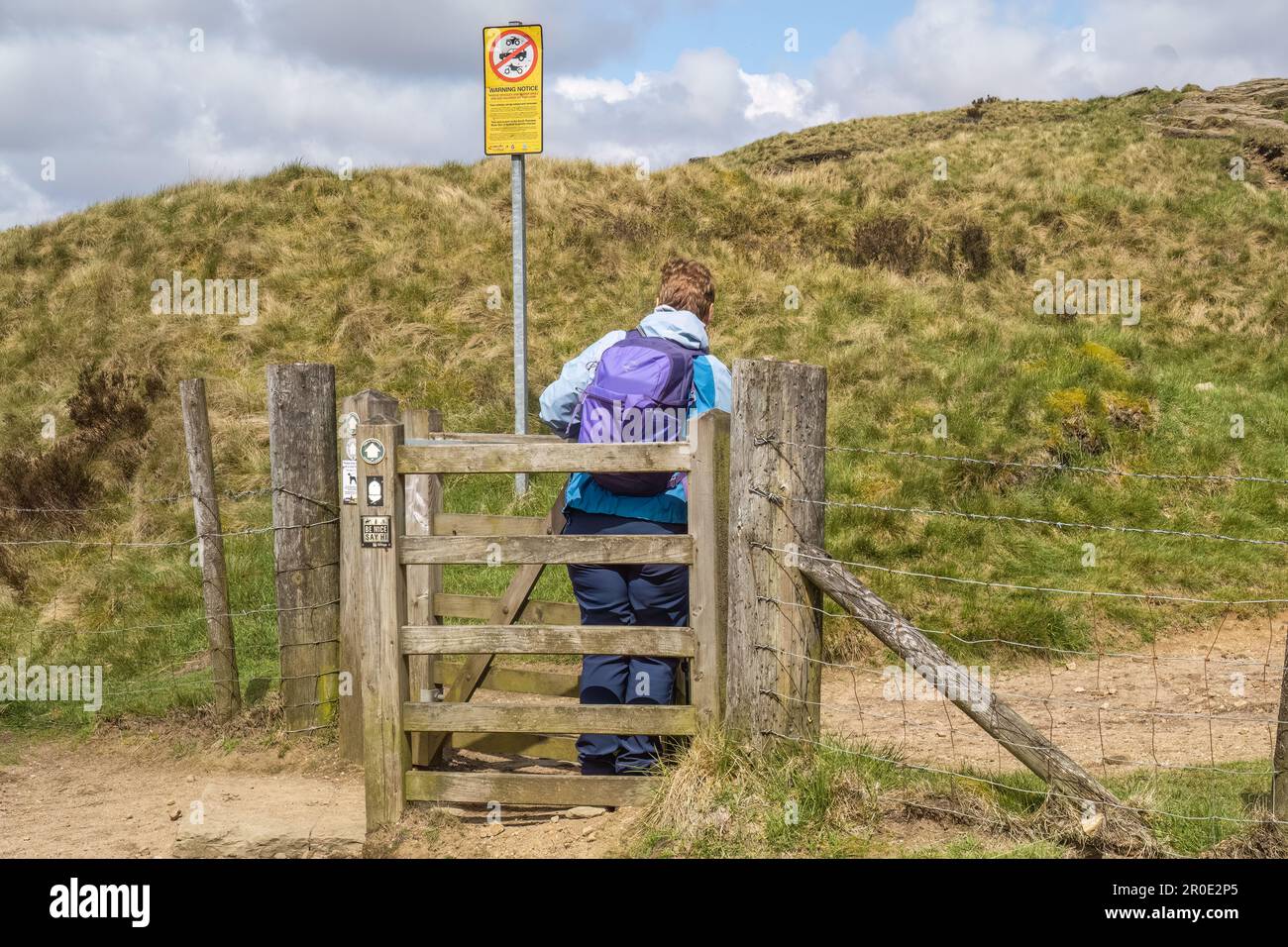 07.05.23 Marsden, West Yorkshire, Vereinigtes Königreich. Eine Frau, die versucht, durch ein Hecktor zu kommen, auf dem Weg zum Pennine Way nahe dem Marsden Moor Stockfoto