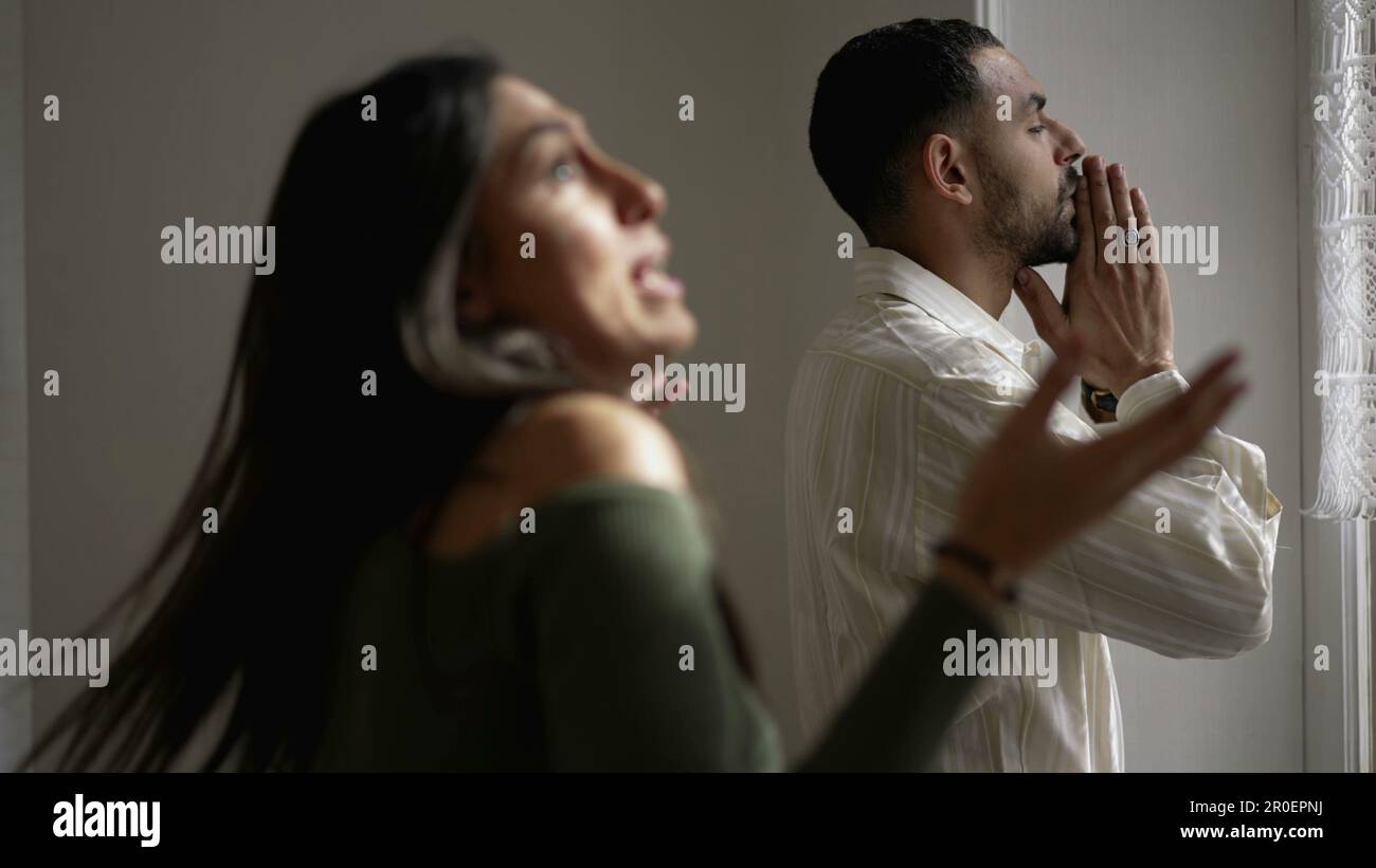 Stille Leiden. Der Freund erträgt die Verhöhnung seiner Freundin, während sie sich in der angespannten Heimdiskussion im Hintergrund bewegt. Ein Paar kämpft in der Krise Stockfoto