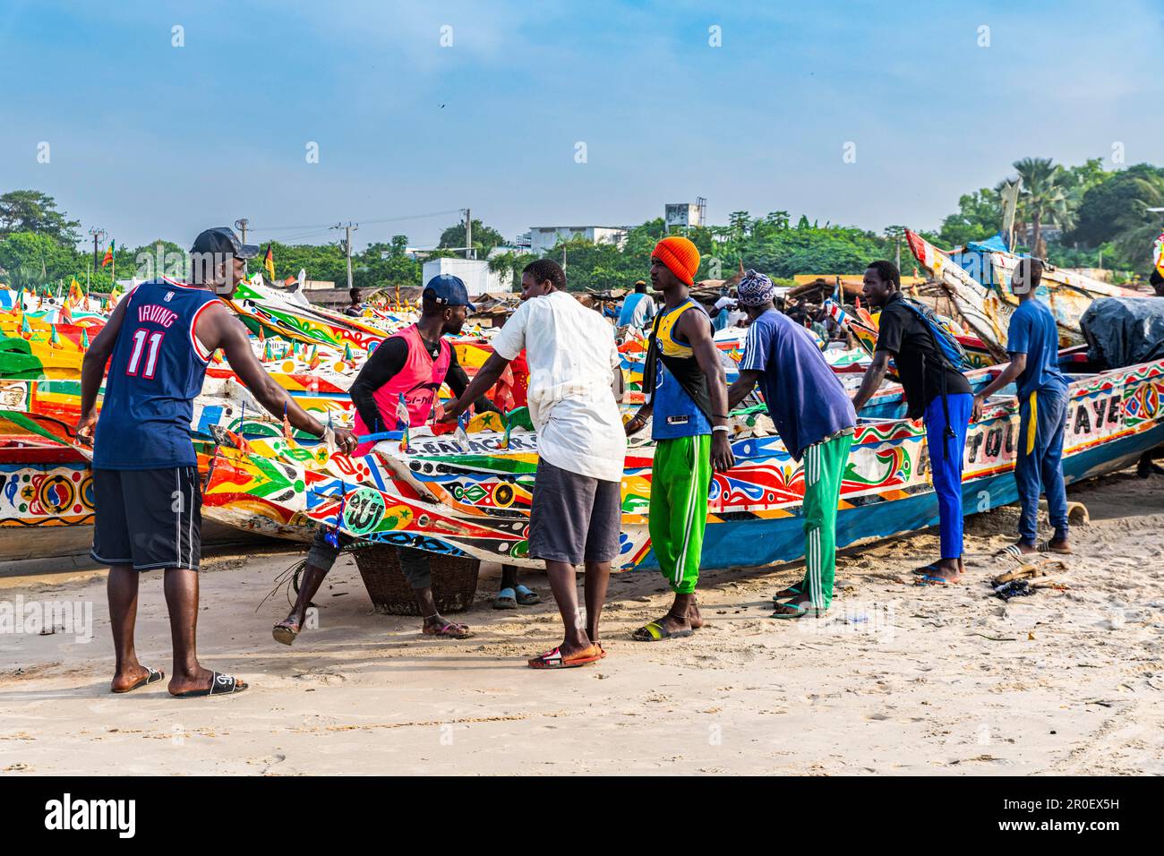 Männer ziehen farbenfrohes Fischerboot, Cap Skirring, Casamance, Senegal Stockfoto