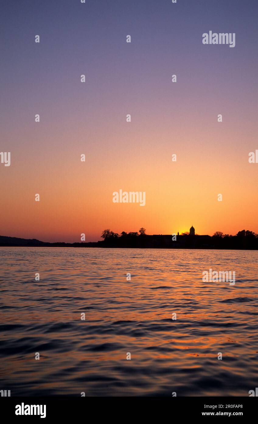 Silhouette der Insel Frauenchiemsee am Chiemsee in der Dämmerung mit glühendem Abendhimmel, Chiemgau, Oberbayern, Bayern, Deutschland Stockfoto