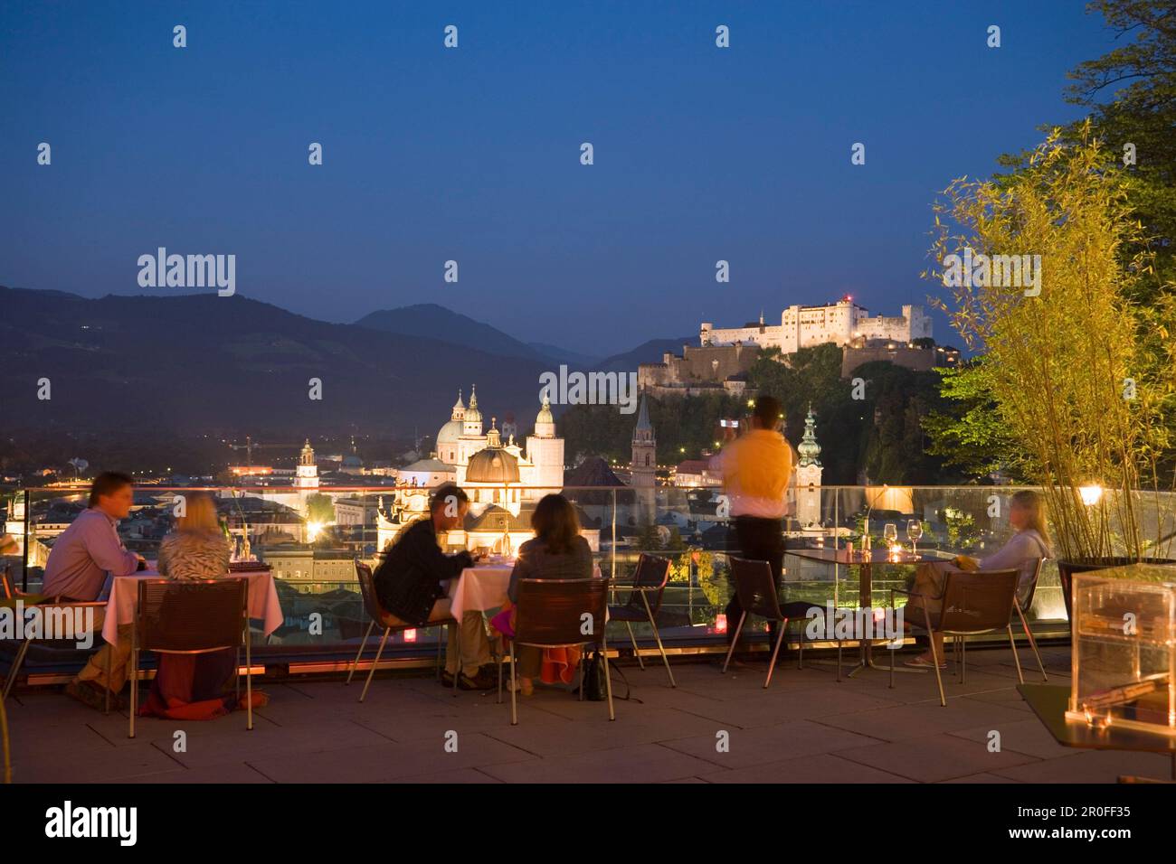 Gäste sitzen abends auf der Terrasse des Restaurants Mönchsberg 32 mit Blick auf die Altstadt mit Festung Hohensalzburg, Salzburg, Salzburg, Österreich, Stockfoto