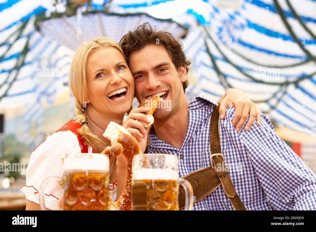 Paar mit Bier und Brezel in einem Bierzelt Stockfoto