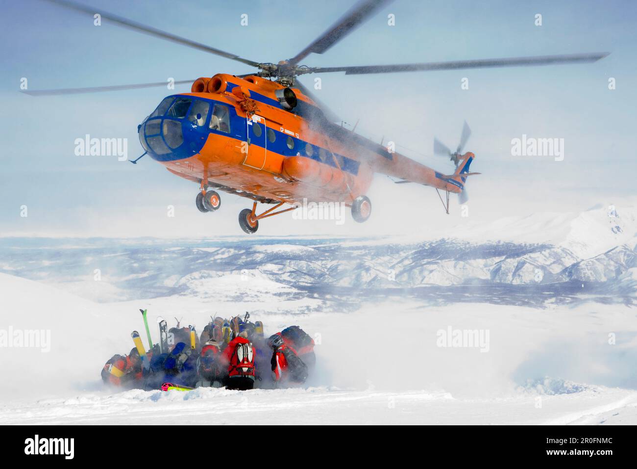 Hubschrauber, der eine Gruppe von Skifahrern in Schnee, Heliskiing, Kamchatka Halbinsel, Sibirien, Russland abholt Stockfoto
