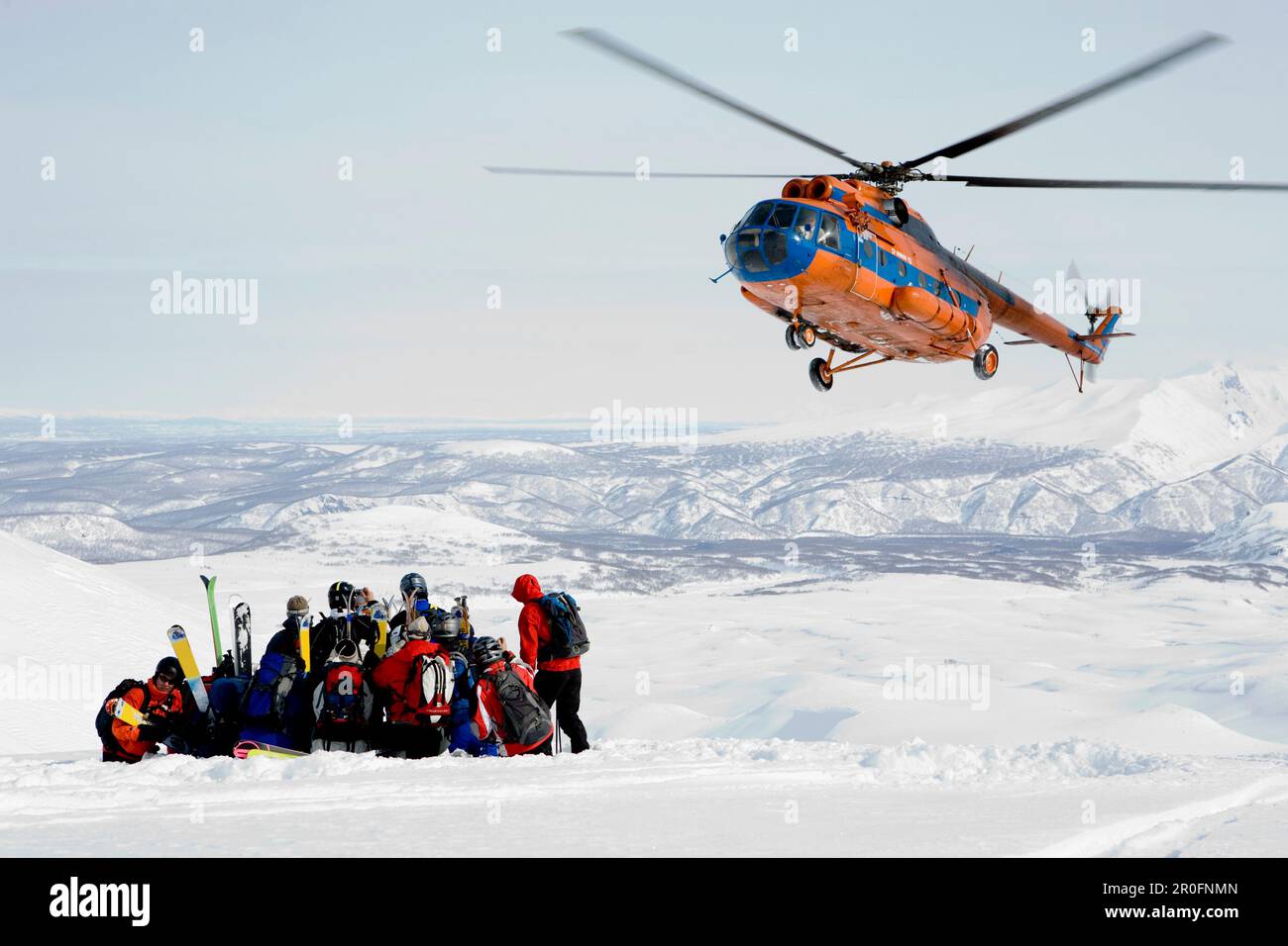 Hubschrauber, der eine Gruppe von Skifahrern in Schnee, Heliskiing, Kamchatka Halbinsel, Sibirien, Russland abholt Stockfoto